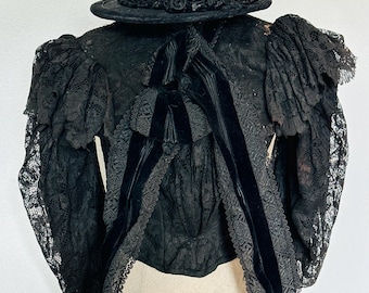 Puede incluir: Una blusa de encaje negro con una cinta de terciopelo y un sombrero de encaje negro.
