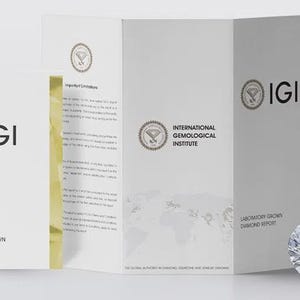 May include: A white IGI Laboratory Grown Diamond Report document with gold foil edges, featuring the International Gemological Institute logo and text, displayed alongside a single, round, brilliant-cut, faceted, clear, sparkling diamond.