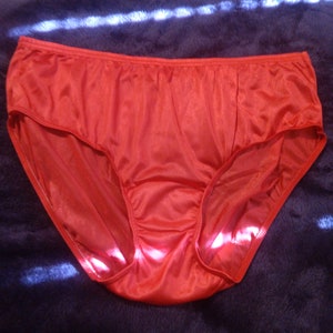 May include: Red satin underwear with a high leg cut and a wide waistband.