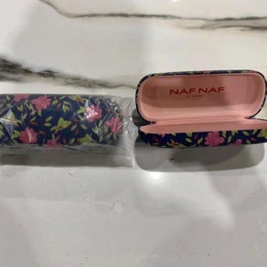 May include: Two floral patterned eyeglass cases. One case is open and has the text "NAF NAF" on the inside. The other case is closed.
