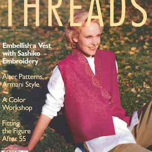 May include: A magazine cover featuring a woman wearing a pink vest with intricate embroidery. The magazine is titled "Threads" and the cover text reads "Embellish a Vest with Sashiko Embroidery".