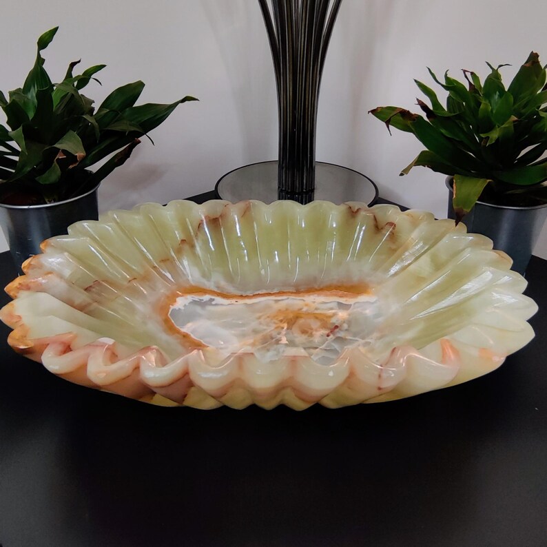 Puede incluir: Un cuenco decorativo ovalado de &oacute;nix con borde festoneado. Presenta una combinaci&oacute;n de colores verde claro y naranja, con un interior veteado. Este objeto decorativo es ideal para exhibir. Dimensiones: aproximadamente 30 cm de largo.