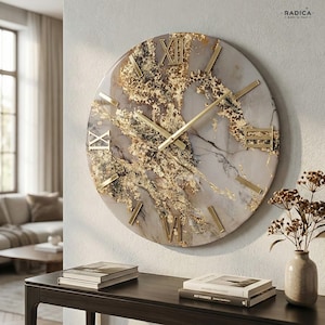Può includere: Un grande orologio da parete rotondo con un quadrante effetto marmo, impreziosito da foglie d'oro e numeri romani dorati. Le lancette dell'orologio sono dorate. L'orologio è montato su una parete chiara. Un elemento di arredo decorativo.