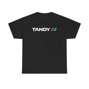 Könnte beinhalten: Schwarzes T-Shirt mit dem Wort "TANDY" in weißen Buchstaben und einem bunten Logo mit drei Streifen.