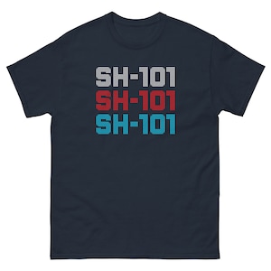 Può includere: Una t-shirt blu navy con il testo "SH-101" ripetuto tre volte in bianco, rosso e blu.