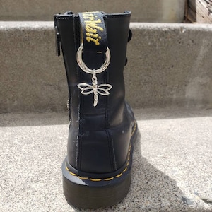 May include: Black leather boots with yellow stitching and a black and yellow zipper. A silver dragonfly charm is attached to a black and yellow strap.
