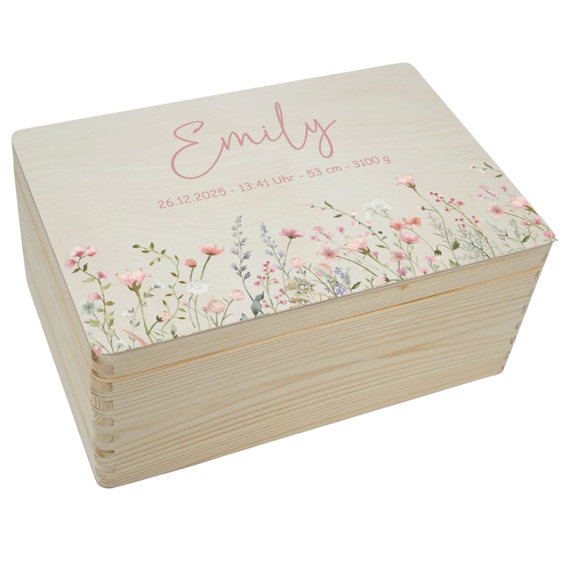 May include: A wooden keepsake box with a light-colored finish. The lid features the name "Emily" in pink script, along with birth details. Delicate floral artwork in pink, white, and green adorns the lid's edge. The box is rectangular with dovetail joints.