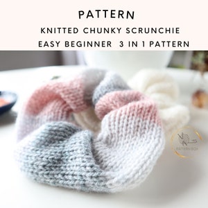 Op de afbeelding: Een gebreide scrunchie in roze, grijs en wit garen. De scrunchie is gemaakt met dik garen en heeft een eenvoudige breisteek. De scrunchie is een beginner-vriendelijk breiproject.