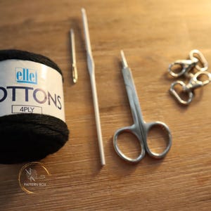 tools you will need, laid out on a table: cotton yarn, needle, hook, scissors, clips