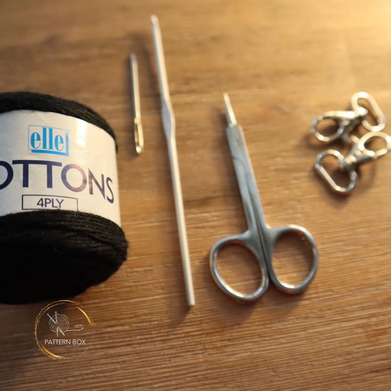 tools you will need, laid out on a table: cotton yarn, needle, hook, scissors, clips
