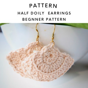 May include: A pair of handmade, light peach-colored crochet earrings with gold-colored hooks. The earrings are in a half-doily fan shape. Text at the top reads "PATTERN HALF DOILY EARRINGS BEGINNER PATTERN."