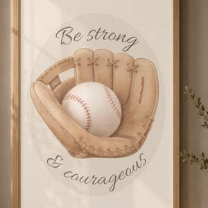 May include: A framed wall art print featuring a tan leather baseball glove holding a white baseball with red stitching. The text "Be strong & courageous" is written in a dark script font above and below the glove, centered on a light background.