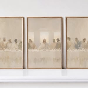 May include: A triptych of framed wall art prints depicting the Last Supper in a muted, neutral beige and cream color palette. The three vertical rectangular frames feature a soft, painterly style showing figures seated at a long table.
