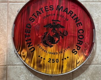 May include: A round wooden decorative piece with a red and yellow gradient. The words "UNITED STATES MARINE CORPS" and "SEMPER FIDELIS" are printed in black, along with an emblem and the number "250".