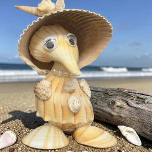 May include: A whimsical sculpture crafted from seashells, resembling a character with googly eyes, a pearl necklace, and a hat. The figure stands on a sandy beach, with additional shells scattered around. The color palette is primarily beige and white.