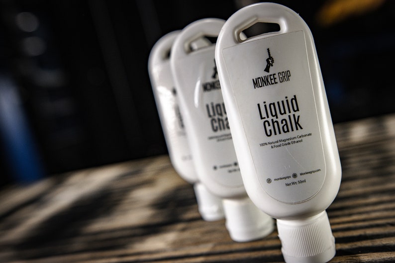 May include: Three white bottles of liquid chalk labelled "Monkee Grip Liquid Chalk 100% Natural Magnesium Carbonate & Food Grade Ethanol Net Wt. 5 fl oz"