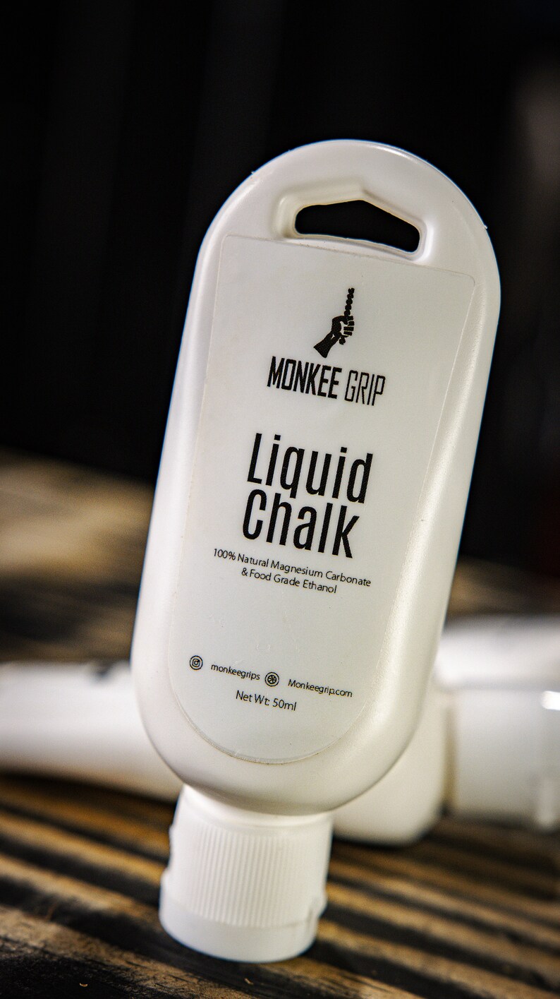 May include: White plastic bottle of liquid chalk with a black label that says "MONKEE GRIP Liquid Chalk 100% Natural Magnesium Carbonate & Food Grade Ethanol" and "monkeegrips Monkeegrip.com Net Wt: 50ml".
