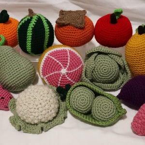 May include: A collection of crocheted fruit and vegetable toys, including a watermelon, a pear, a strawberry, a cauliflower, a pumpkin, a watermelon, a grapefruit, a carrot, a pea pod, a beet, a  broccoli, and a  watermelon.