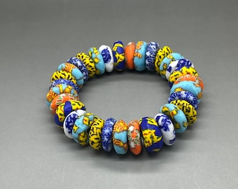 May include: A colorful bracelet made of small, round beads with blue, yellow, orange, and white patterns. The beads are arranged in a circle and are strung together on a clear string.
