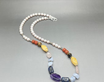 Può includere: Una collana di perle con una varietà di perline di pietre preziose, tra cui ametista, lapislazzuli e quarzo rosa. La collana è realizzata con chiusure in argento.