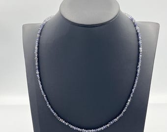 May include: A delicate necklace made of small, light blue and clear gemstone beads.