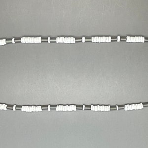 May include: A black and white beaded necklace with a silver clasp. The necklace is made of small, round beads.
