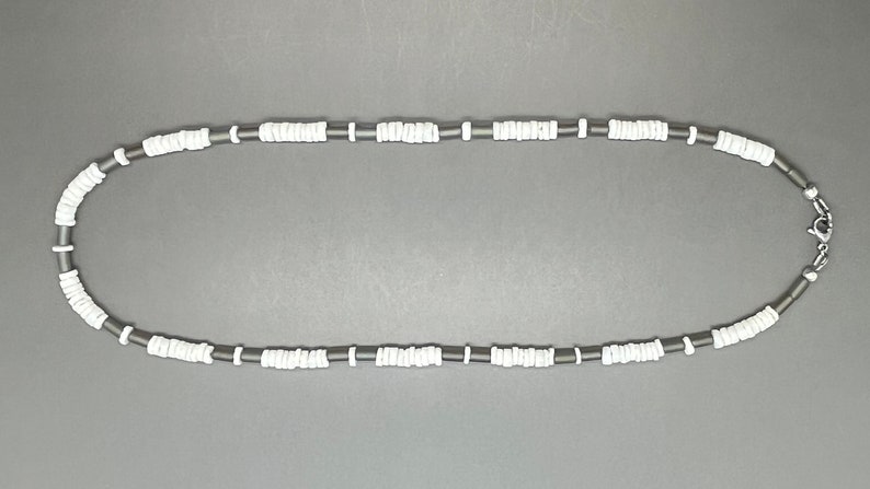 May include: A black and white beaded necklace with a silver clasp. The necklace is made of small, round beads.