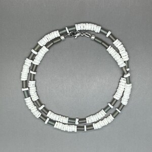 May include: A double-strand necklace made of white and gray beads. The necklace has a silver clasp.