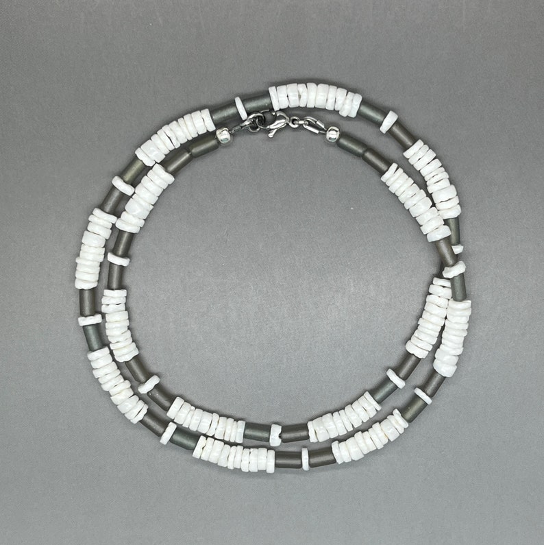 May include: A double-strand necklace made of white and gray beads. The necklace has a silver clasp.