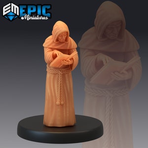 May include: A miniature figurine of a robed monk reading a book. The figure is in a light brown color, with a hood and a rope belt. The base is black, and the figure is set against a dark background. The logo "EM EPIC Miniatures" is in the top left corner.