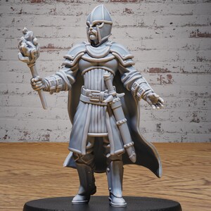 Puede incluir: Una figura en miniatura de plástico gris de un caballero con casco y sosteniendo una antorcha. El caballero lleva armadura y una capa. La figura está de pie sobre una base negra.