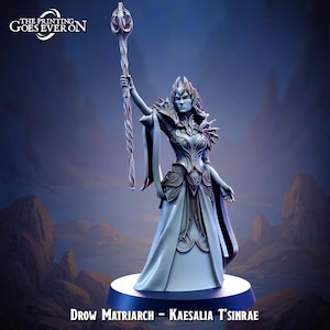 May include: A detailed figurine of a Drow Matriarch, Kaesalia T'Sinrae, holding a staff aloft. The figure is in a flowing gown with intricate armor details. The text "THE PRINTING GOES EVER ON" is at the top left. The base is dark blue.