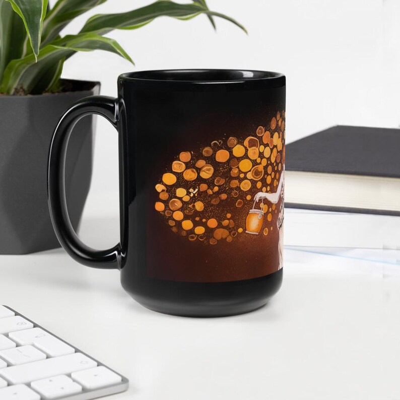 May include: Black ceramic mug featuring a whimsical illustration of a figure holding a lantern, with a cluster of golden orbs. The design is set against a gradient background of brown and gold. The mug has a large handle.