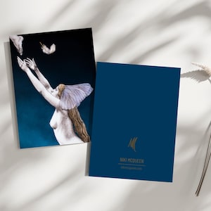 Puede incluir: Dos tarjetas de felicitación. Una tarjeta presenta una ilustración de una mujer con los brazos extendidos, un tocado de mariposa y una pluma. La otra tarjeta es azul marino con texto dorado y un logotipo "NIKI MCQUEEN".