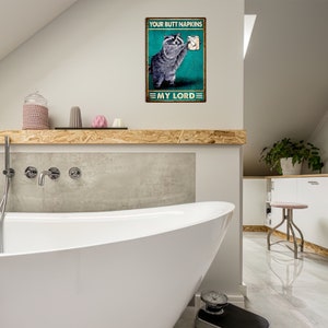 May include: A rectangular metal sign featuring a raccoon holding toilet paper. The sign reads "YOUR BUTT NAPKINS" at the top and "MY LORD" at the bottom. The background is teal with a distressed effect.