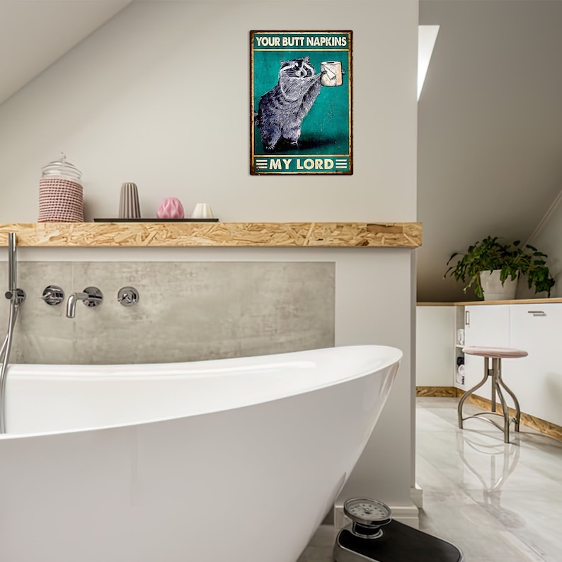 May include: A rectangular metal sign featuring a raccoon holding toilet paper. The sign reads "YOUR BUTT NAPKINS" at the top and "MY LORD" at the bottom. The background is teal with a distressed effect.
