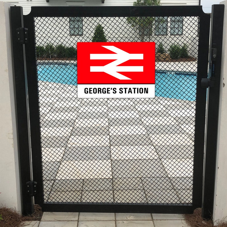 May include: A black metal gate with a red and white sign that says "GEORGE'S STATION" and a white symbol with two diagonal lines and an arrow pointing to the right. The gate is in front of a swimming pool.