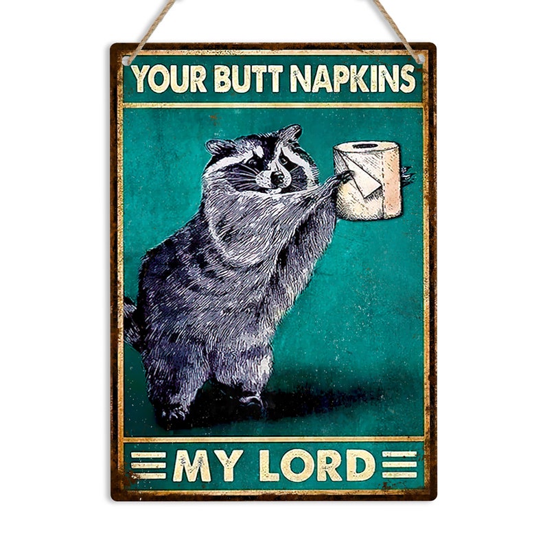 May include: A rectangular metal sign featuring a raccoon presenting a toilet roll. The sign reads "YOUR BUTT NAPKINS" and "MY LORD". The background is teal with a distressed effect, and the sign is framed in a rustic style.