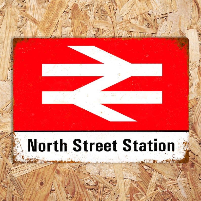 May include: A red and white metal sign with the text "North Street Station" and a white railway symbol. The sign has a distressed, rusty look.