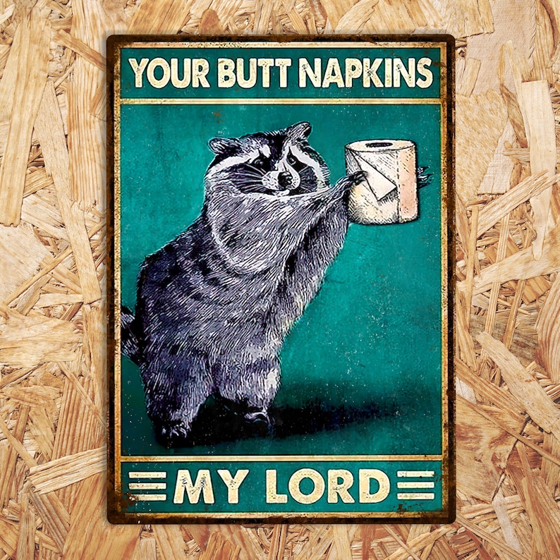 May include: A rectangular metal sign featuring a raccoon offering a toilet roll. The sign reads "YOUR BUTT NAPKINS" above and "MY LORD" below. The background is teal, with a distressed, vintage aesthetic. The sign is designed to look old.