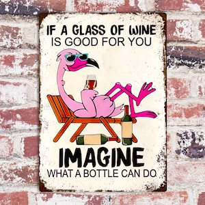 Puede incluir: Un flamenco rosa con gafas de sol se relaja en una tumbona con una copa de vino. El texto en el cartel dice "Si un vaso de vino es bueno para ti, imagina lo que puede hacer una botella."