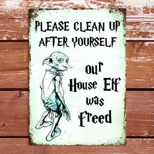 May include: A white metal sign with a green tint and a cartoon image of a house elf. The sign reads "Please clean up after yourself, our house elf was freed."