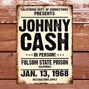 May include: A vintage metal sign with the text "JOHNNY CASH IN PERSON!" in bold black letters. The sign also includes the text "FOLSOM STATE PRISON (CALIFORNIA) JAN. 13, 1968." The sign has a distressed, aged appearance.