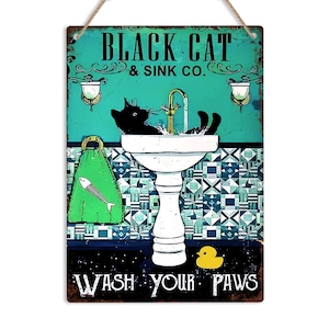 K&ouml;nnte beinhalten: Ein Vintage-Schild aus Metall mit einer schwarzen Katze, die sich die Pfoten in einem wei&szlig;en Porzellanwaschbecken w&auml;scht. Das Schild tr&auml;gt die Aufschrift "Black Cat & Sink Co." und "Wash Your Paws".