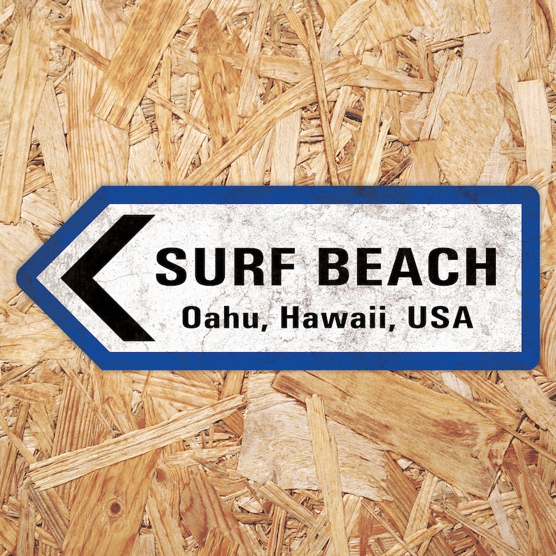 Puede incluir: Un letrero azul y blanco con una flecha negra apuntando hacia la izquierda. El letrero dice "Surf Beach, Oahu, Hawaii, USA".