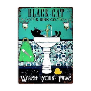 K&ouml;nnte beinhalten: Ein Vintage-Schild aus Metall mit einer schwarzen Katze, die sich in einem wei&szlig;en Porzellanwaschbecken w&auml;scht. Das Schild tr&auml;gt die Aufschrift "Black Cat & Sink Co." und "Wash Your Paws". Der Hintergrund ist t&uuml;rkisblau mit einem gr&uuml;nen Handtuch und einer gelben Gummi-Ente.