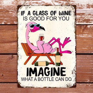 Puede incluir: Un flamenco rosa con gafas de sol se sienta en una tumbona con una copa de vino. El cartel dice "Si un vaso de vino es bueno para ti, imagina lo que puede hacer una botella."