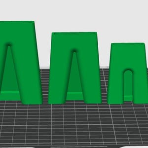 May include: Three green, trapezoidal-shaped objects of varying heights arranged in a row. Each object features a central vertical cutout that creates two distinct legs at the base, with a flat top surface and smooth, solid-colored construction.