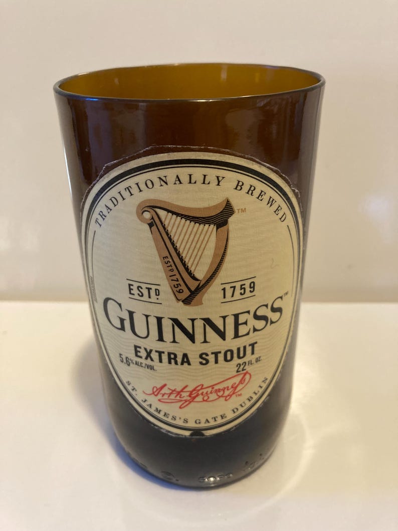 May include: A brown glass beer bottle with a label that reads "Traditionally Brewed", "Est. 1759", "Guinness Extra Stout", "5.6% Alc/Vol", "22 fl. oz.", "St. James's Gate Dublin", and "Arthur Guinness".