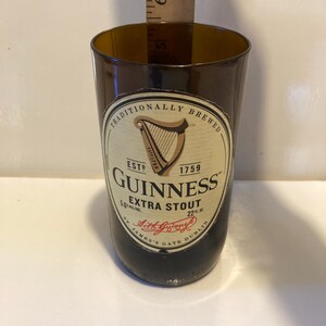 May include: A brown glass bottle with a label that reads "Traditionally Brewed" and "Guinness Extra Stout". The label also includes the Guinness harp logo and the text "Est. 1759".